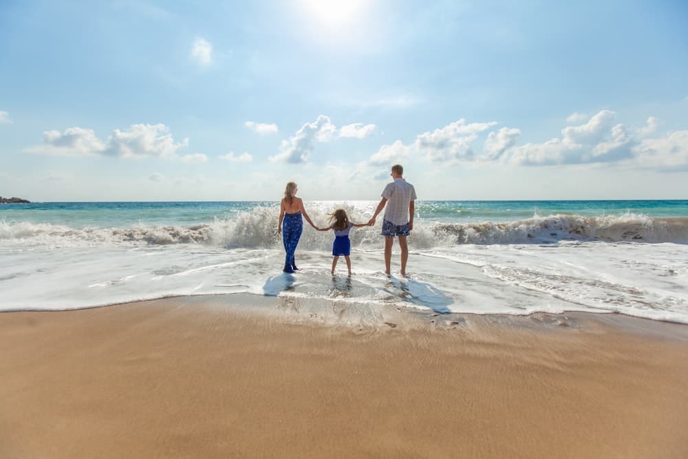 Família de mãos dadas caminhando na beira do mar